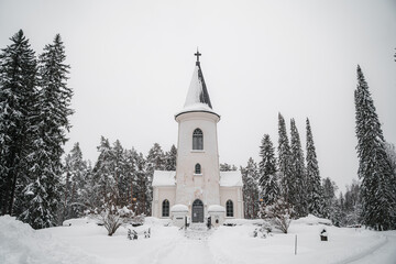 Fototapeta na wymiar Small chapel church in woods during snowy winter
