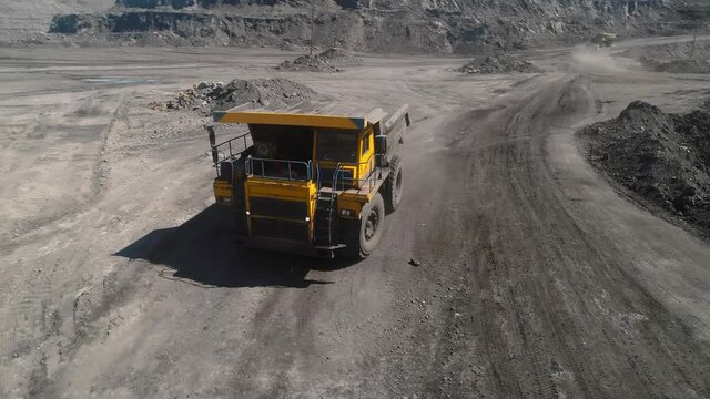 Large quarry dump truck. Loading rock in dumper. Loading coal into truck. Mining car machinery to transport coal. Open pit mine quarrying extractive industry stripping work. Big Yellow Mining Trucks