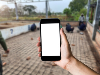 Hand holding white mobile phone with blank white screen in team of architects is building.