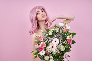 Woman with colored pink strong hair holds a bouquet of beautiful flowers in her hands. Natural dyed hair beautiful makeup, strong roots