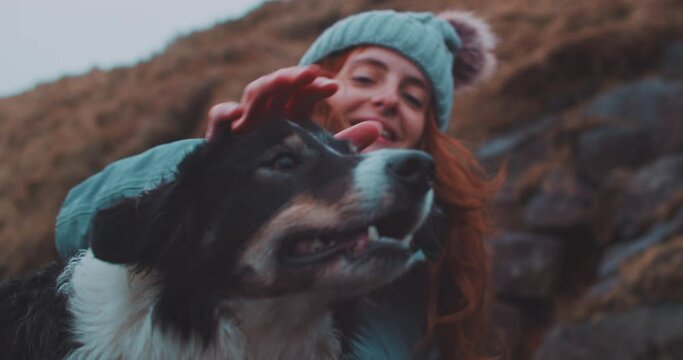 Young woman petting a dog and smiling. 