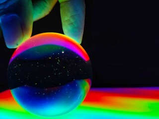 A crystal ball holding by hand with colourful lighting effect in noise and grain due to low light. 
