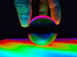 A crystal ball holding by hand with colourful lighting effect in noise and grain due to low light. 