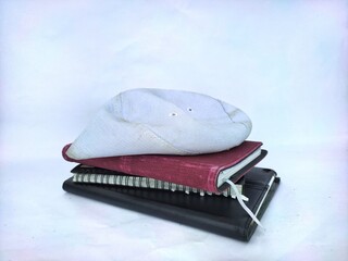 Stacking of diaries with a prayer cap isolated on white background.