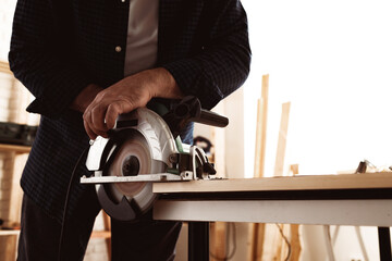 Carpenter hands cutting wood with electrical saw