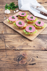 Sandwiches with lettuce leaves and sliced salami sausage on a wooden Board. top view copy space