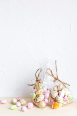 Obraz premium Chocolate Easter eggs, candy in colorful glaze in a transparent bag on a light background. Happy easter. Preparation for the holiday, gift wrapping. Sweet shop, sweet store. Vertical, copy space.