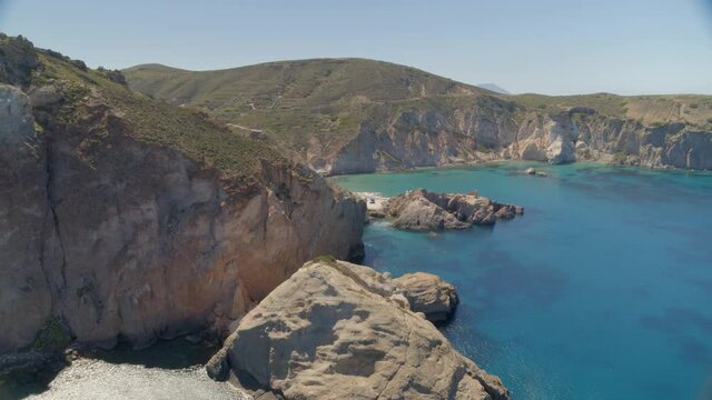 Flying Over Cliffs Cascading into the Aegean Sea and Towards Small Bay in Milos