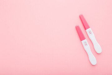 Pregnancy tests with one stripe and two stripes on light pink table background. Pastel color....