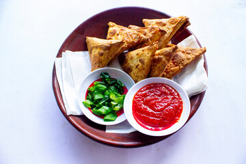 Samosa, samsa or somsa are triangular fried pastries or pastri served with tomato sauce and leek slice, on table