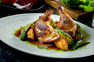 Fried chicken thighs with yellow and green sauce garnished with mashed potatoes and avakodos, served on a white plate. Restaurant food. Meat dish