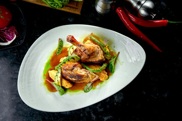 Fried chicken thighs with yellow and green sauce garnished with mashed potatoes and avakodos, served on a white plate. Restaurant food. Meat dish