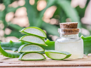 Fresh aloe leaves and aloe gel in the cosmetic jar on wooden table.