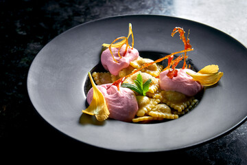 Sweet ravioli with cherries and pink ice cream served in a black plate on a dark marble background. Restaurant food. Italian Cuisine. Dumplings with sweet filling