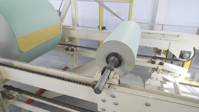 Rotation of a roll of paper for drywall on plant. Manufacturing plasterboard sheets by conveyor on factory