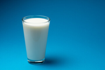 Glass of fresh milk isolated on blue background.