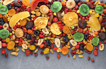 Dried fruits and berries on gray background top view. Lemons, oranges, raisins, cranberries, kiwi, cherries, ginger, plums, strawberries, candied fruits,  tangerines, dates, figs, melon, mango.