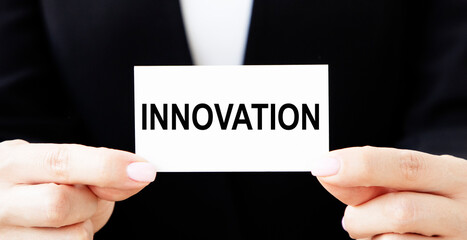 The girl businessman puts in the pocket of a jacket a business card with the text INNOVATION.