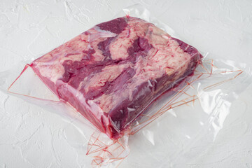 Pastrami meat packed in vacuum plastic bags, on white stone  background , with copyspace  and space...