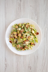 Homemade Bacon Avocado Caesar Salad with Cheese and Croutons on a white wooden background, top view. Flat lay, overhead, from above.