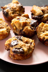 Homemade Chocolate Banana Bread Pudding on a pink plate on a black surface, low angle view. Close-up.