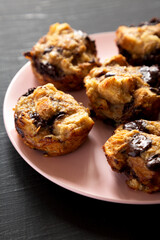 Homemade Chocolate Banana Bread Pudding on a pink plate on a black surface, side view. Close-up.