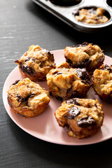 Homemade Chocolate Banana Bread Pudding on a pink plate on a black background, side view.