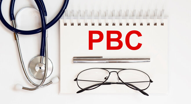 stethoscope,glasses and pen with notepad with text PBC