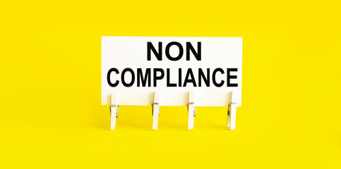 text NON COMLIANCE on the white short note paper on yellow background