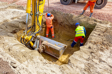 Workers are using shovels to set up right measures in square trench