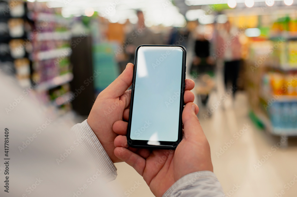 Poster mock-up of a smartphone with a white screen in the hands of a man. phone on the background of in a s