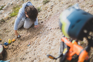 Manos de un chico joven jugando con vehículos de construcción en la arena