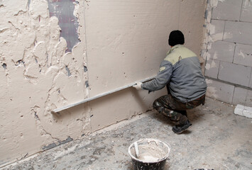 A worker plasters the walls in the room.