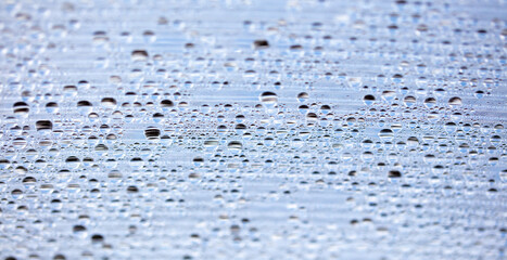Water drops on blue glass as an abstract background.