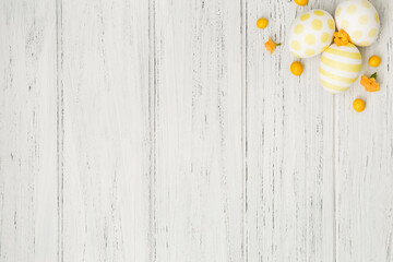 Spring Easter background white wooden table with eggs and yellow flowers and copy space, flat lay