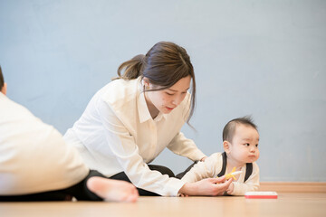 室内で、赤ちゃんと遊ぶお母さん