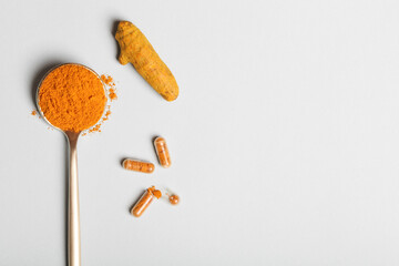 health care lifestyle concept. spoon with turmeric powder, root and pills on blue background. flat...