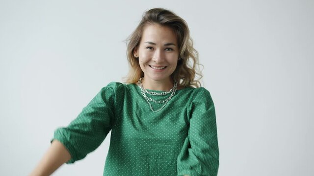 Slow motion portrait of cheerful young woman making dab dance movement smiling having fun on white background. Happiness and expressions concept.
