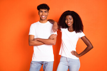 Photo of young happy positive good mood cool afro couple friends stand together wear white t-shirt isolated on orange color background