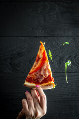 Top view of hand take homemade pizza with arugula isolated on black background. vertical image....