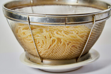 Long spaghetti in an iron colander on a white background
