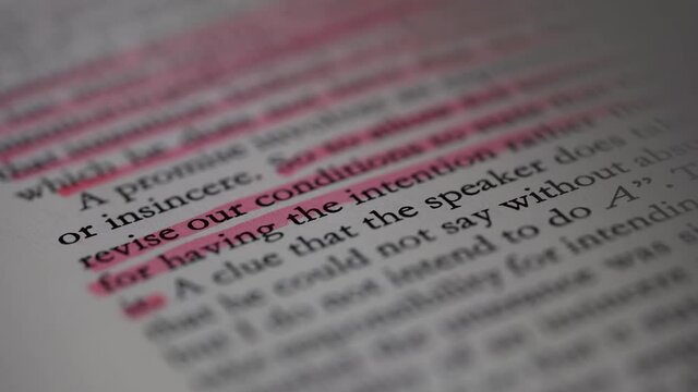 Flipping of white pages with English text in slow motion. The main theses from the book are highlighted in pink marker. Part of the text is blurry. Education concept. Close up.