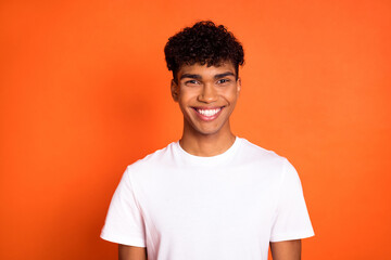 Portrait of satisfied young dark skin person toothy smile look camera isolated on orange color background