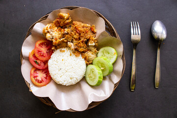 ayam geprek or chicken crush or chicken smashed is indonesian food made from made fried chicken pounded with chili and garlic flavor and served with vegetables and rice