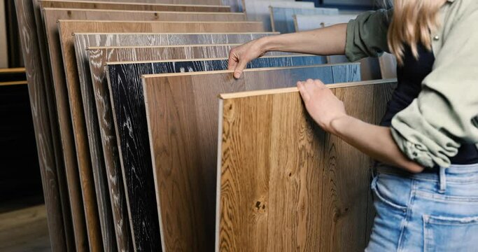 woman choosing wood texture laminate floor in flooring store