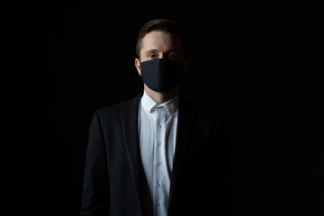 Portrait of handsome confident young businessman with medical mask looking at camera. Medicine and health care concept. 