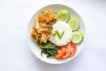 ayam geprek or chicken crush or chicken smashed is indonesian food made from made fried chicken pounded with chilli and garlic flavour and served with vegetables and rice, isolated on white background
