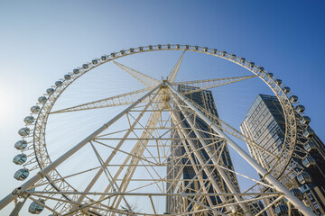 A huge ferris wheel in a modern city against blue sky