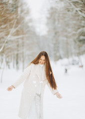 Fototapeta na wymiar Winter portrait of a merry young woman playing with snow at the park