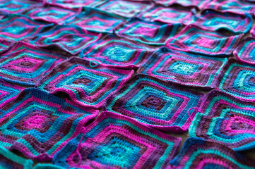 Fototapeta premium Crochet product from multicolored threads. Many squares crocheted. Handmade backdrop.